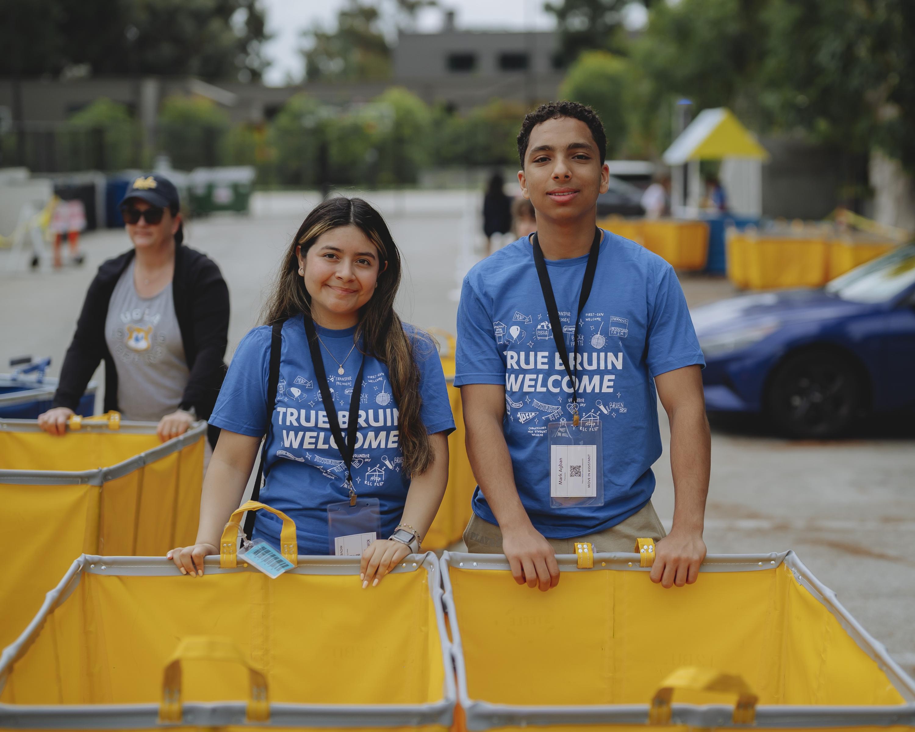 Photo of two True Bruin Ambassadors standing with a cart.