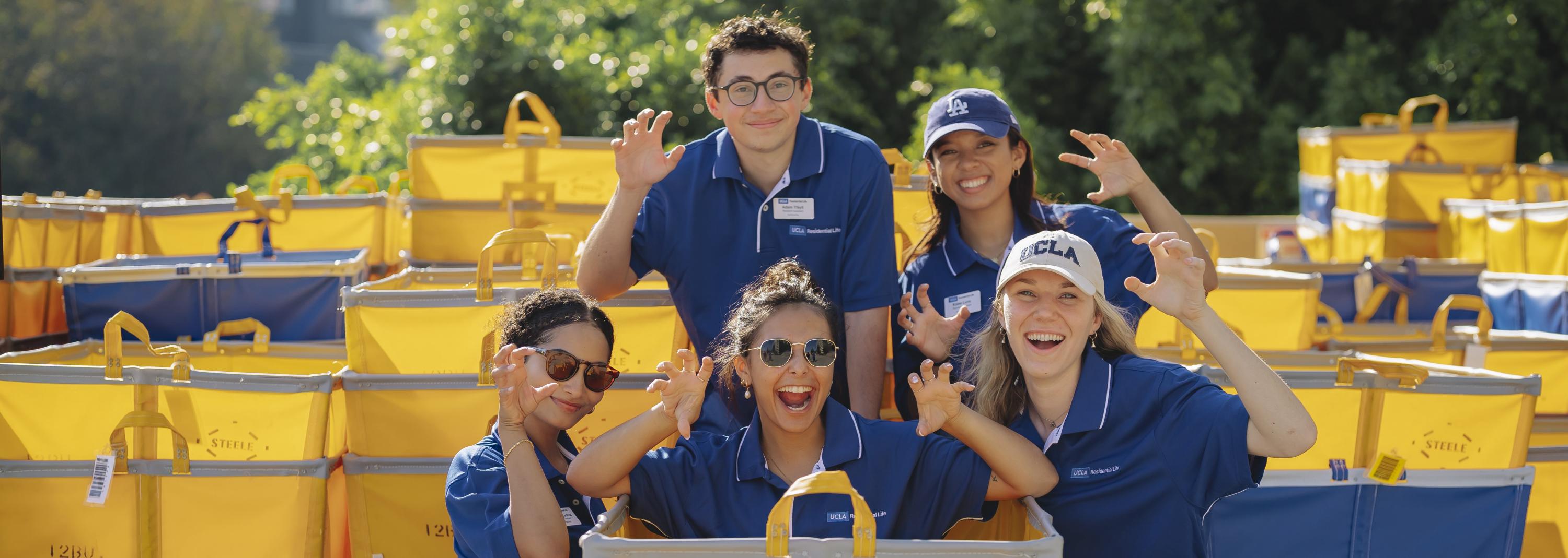 Students in blue Res Life polos posing around move-in carts