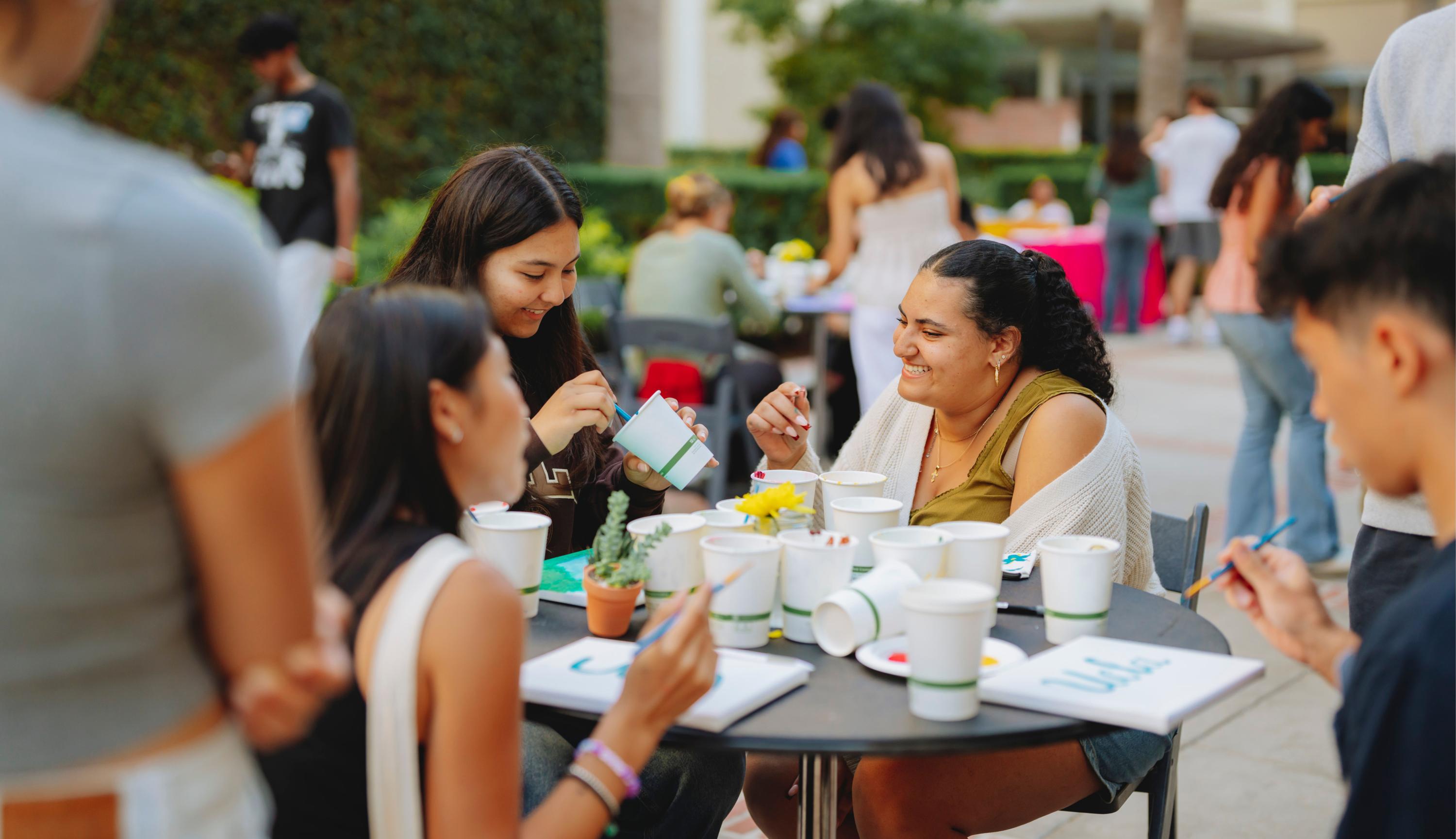 students painting paper cups, smiling
