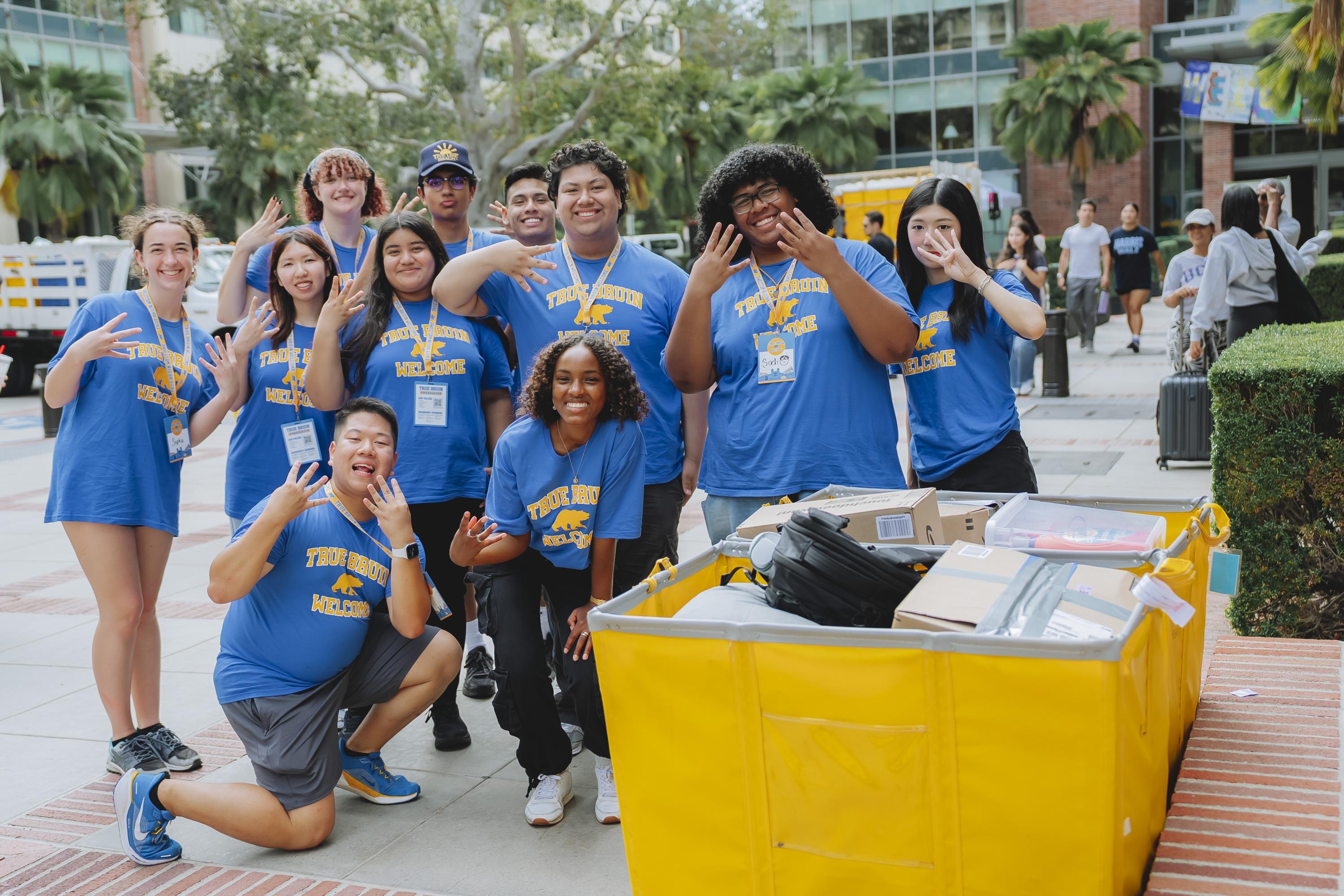 True Bruin Ambassadors posing around a yellow move-in cart.