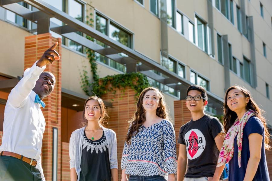 Residential Life staff pointing towards something out of frame, four UCLA students look towards the pointed direction