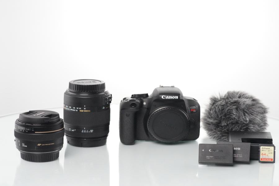 Image displays two lenses, a camera, two batteries and a charger, and an SD card as well as a shotgun microphone