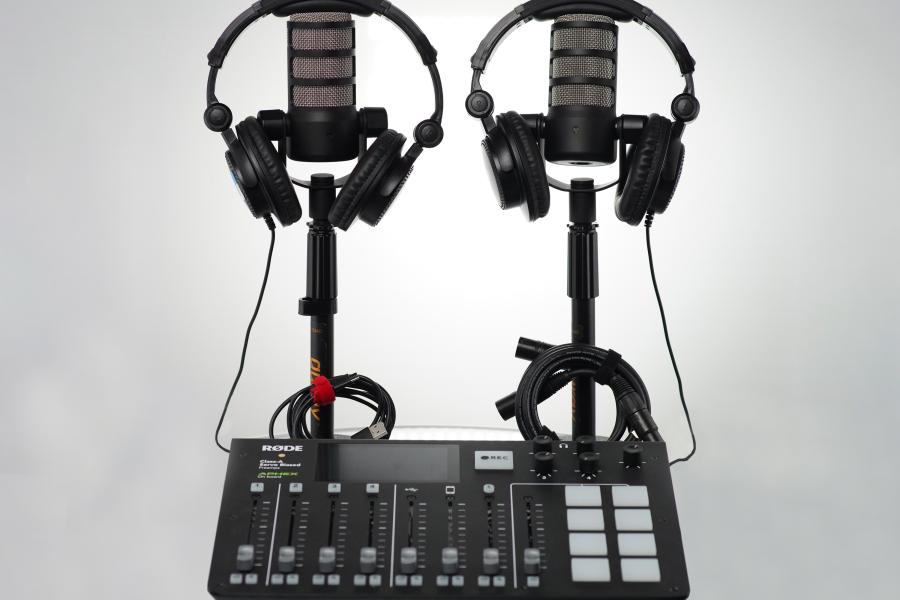 image displays two microphones with headphones laying ontop. Below is a audio interface for the microphones and headphones. 