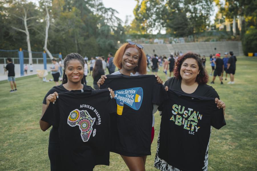 Students and staff smiling at Sunset Recreation holding up LLC t-shirts